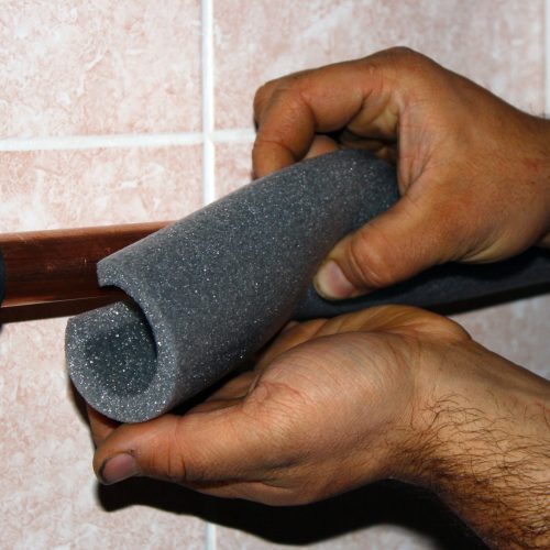 Worker cuts the foam insulation for pipes